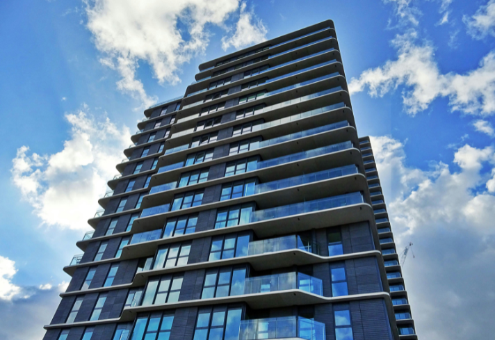 An example of a building Parity can work with - a tall gray multifamily rental building with glass windows and glass balconies.