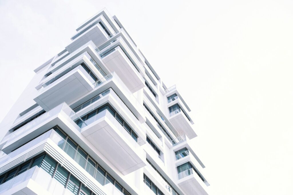 A modern white multifamily building with a lot of glass windows and balconies. This type of building would be a great fit for Parity's Optimizer service.