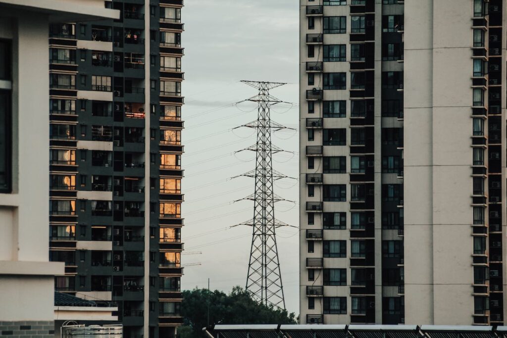 Transmission tower with 2 buildings in front of it. Parity's Optimizer service works with the grid through demand response automation.