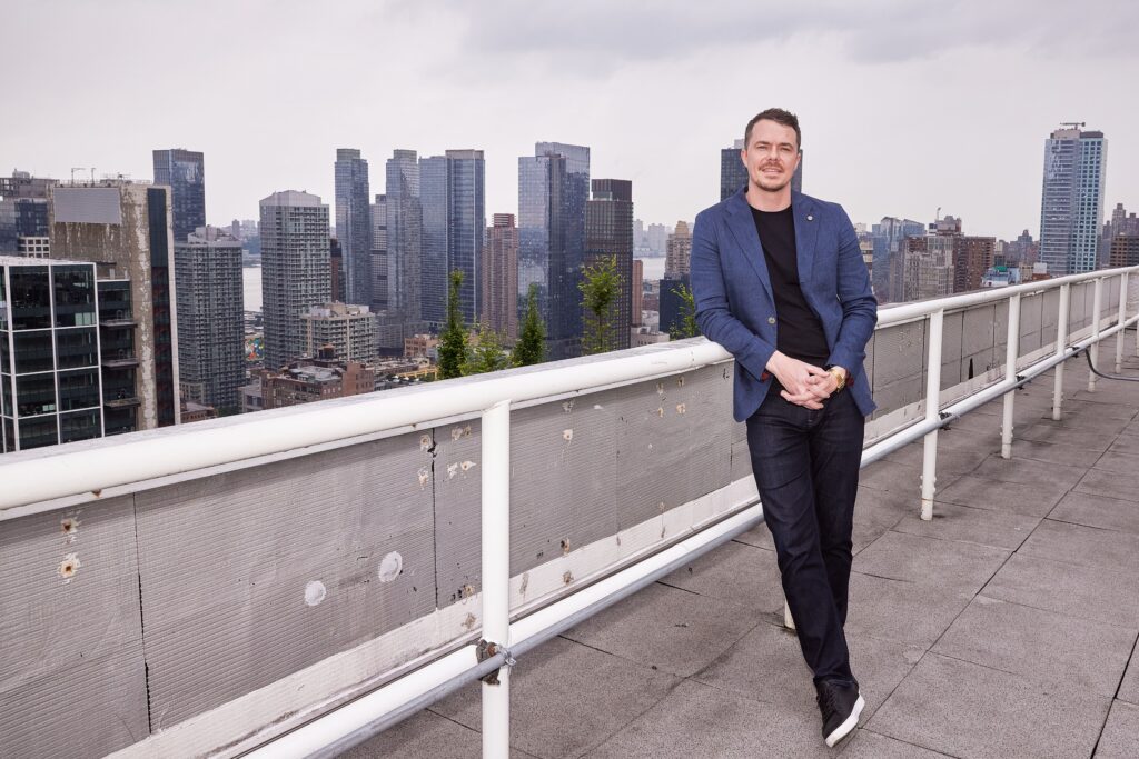 Brad Pilgrim is on top of a clinet's building in NYC. posing for a photoshoot to announce Parity's Series B funding.